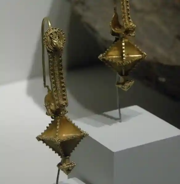 Gold earrings with a diamond pendant that looks like a 3D cross